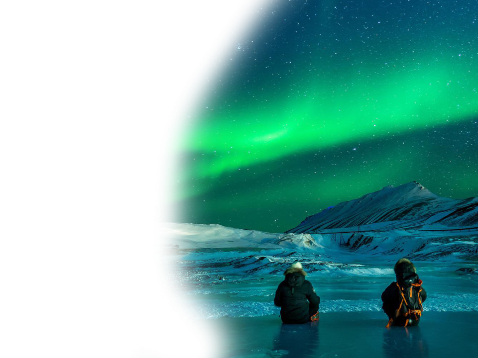 Two people watching the northern lights over a snowy landscape at night.