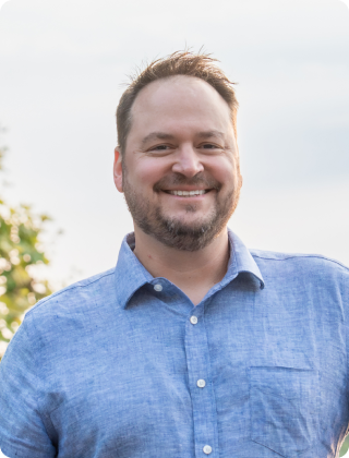 Smiling man in a blue shirt outside.